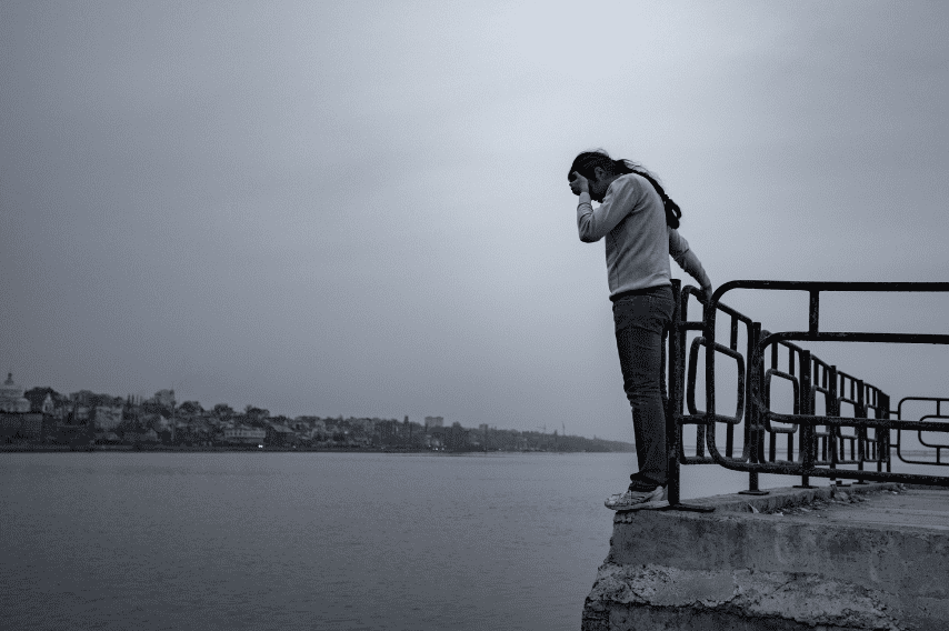 Person on ledge over river contemplating suicde